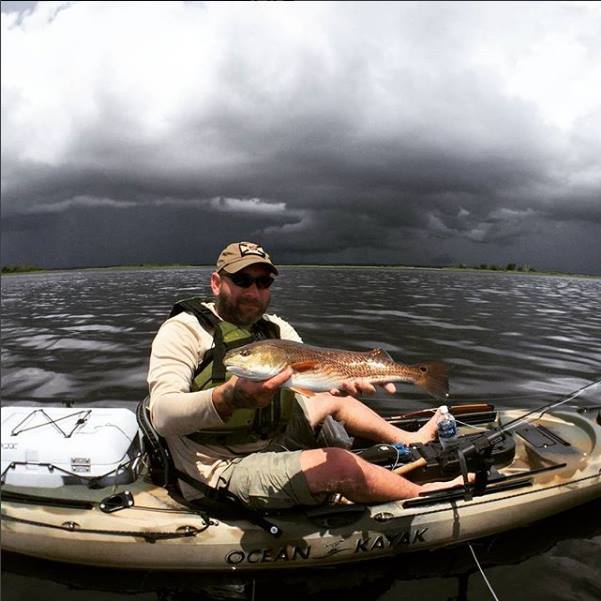 a picture of a kayak fisherman holding a redfish they caught on a crystal river kayak fishing charter