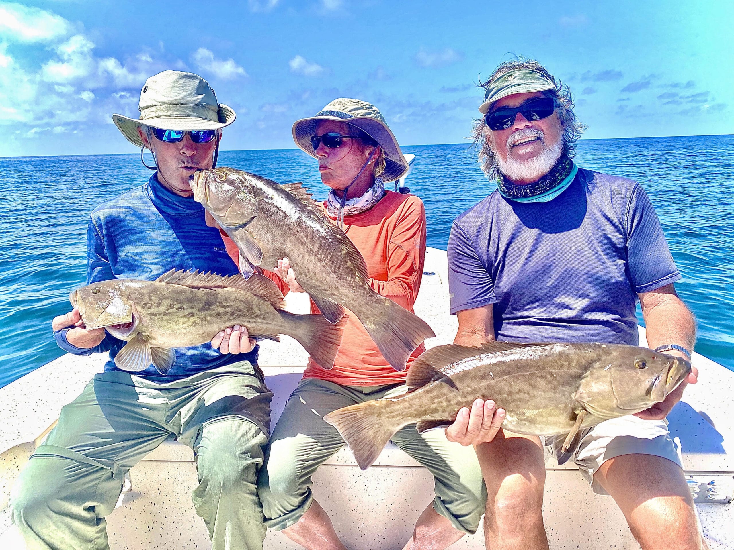 a group of fisherman holding grouper they caught in Crystal River