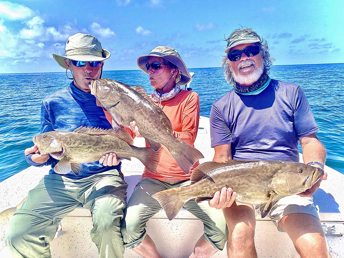 a group of fisherman holding fresh caught grouper in crystal river