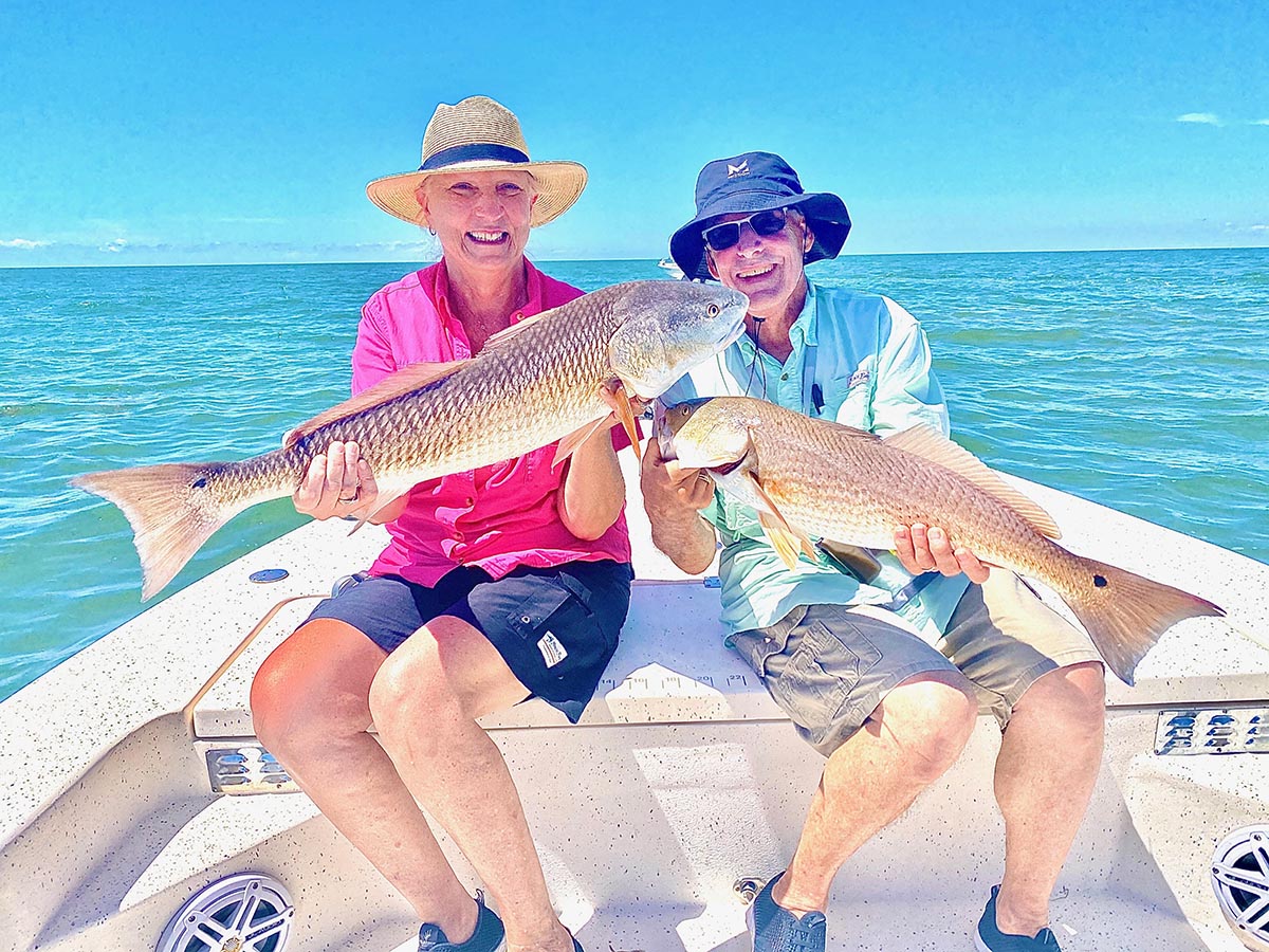 A husband and wife holding redfish they caught on a family fishing charter in crystal river.