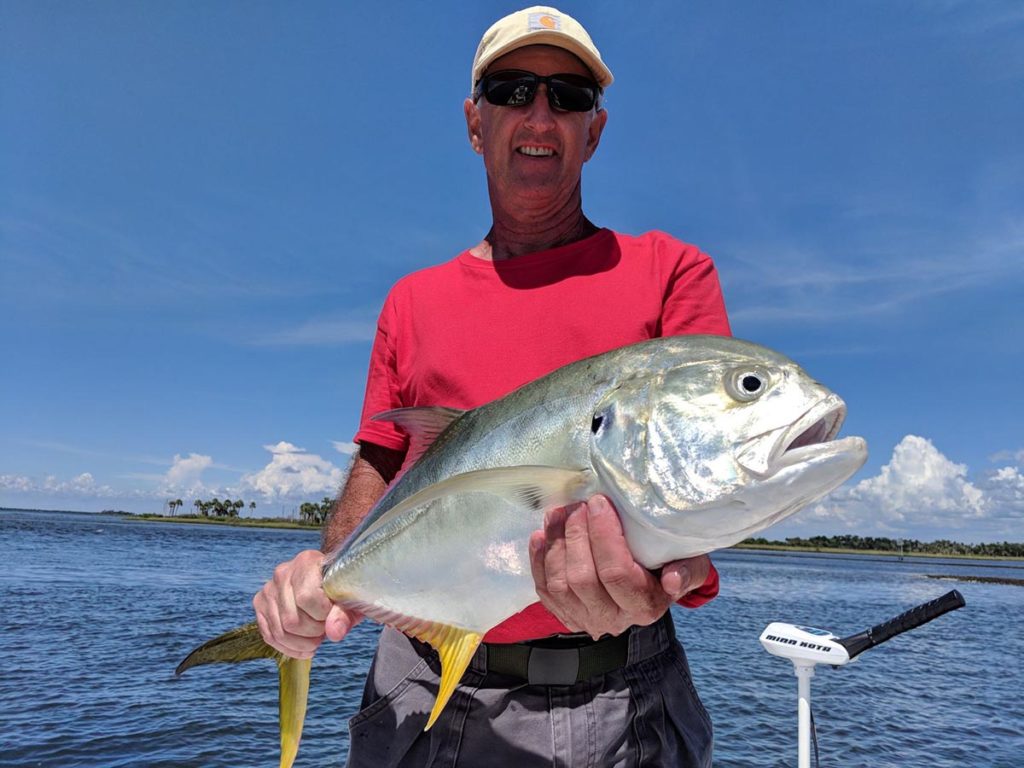 a fisherman holding a large jack crevalle he caught on a crystal river fishing charter.