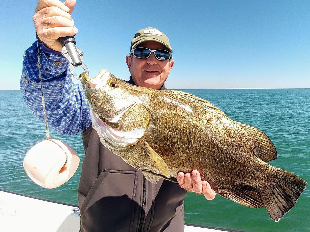 a fisherman holding a tripletail he caught