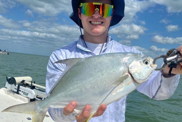 a picture of a fisherman holding a pompano they caught on a crystal river fishing charter