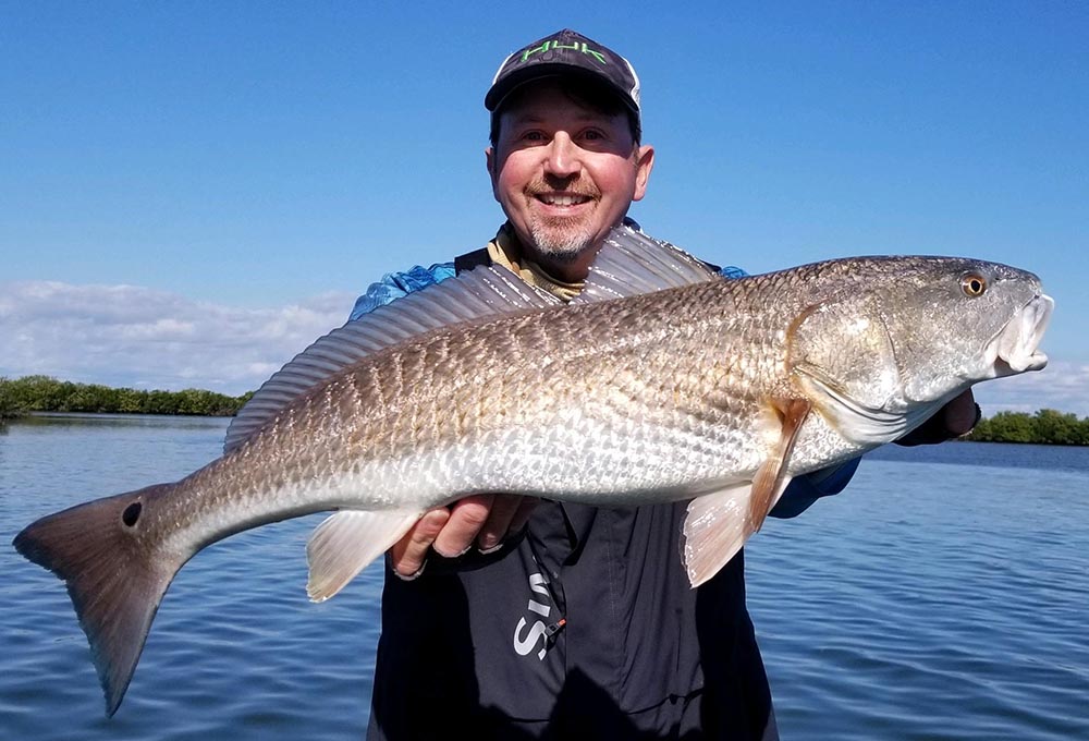 a crystal river inshore fishing charter client holding a redfish