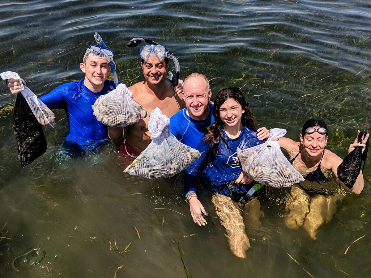 a picture of a family in the water with fresh caught scallops