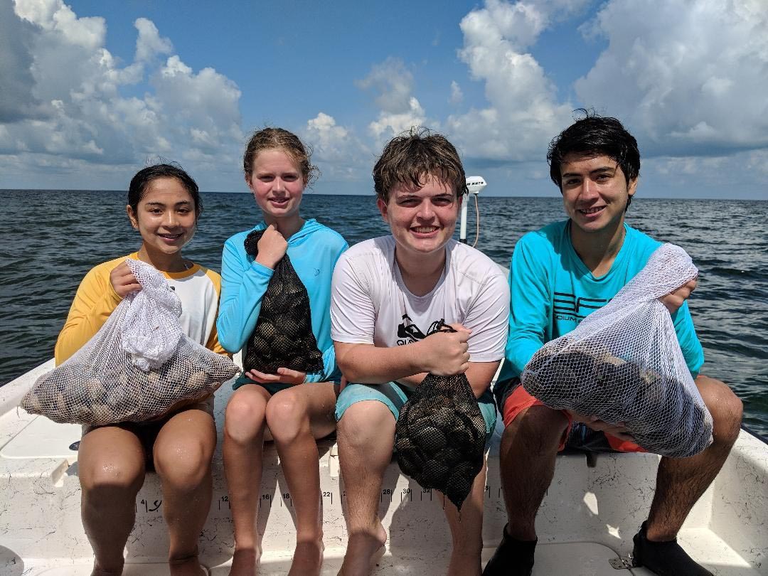 a picture of four people holding bags full of scallops